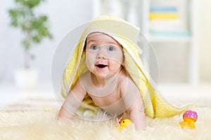 Happy baby under towel indoor after bathing