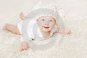 Happy Baby in White Knitted Hat Crawling on White Blanket