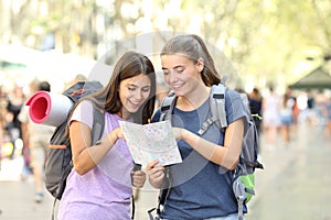 Happy backpackers consulting a paper guide in the street photo