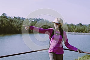 Happy backpacking woman standing with hands pointing something and looking beautiful view at outdoor