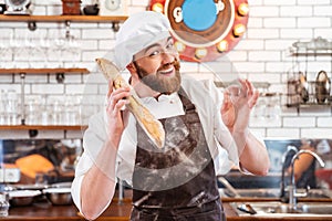 Happy baker holding loaf of bread and showing ok sign