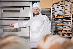 Happy baker leaning on professional oven