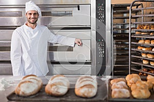 Happy baker leaning on professional oven