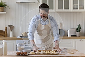 Happy baker man in craft apron baking in home kitchen