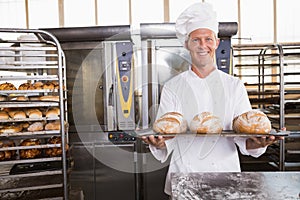 Happy baker showing tray of fresh bread