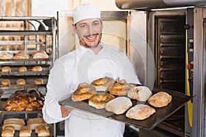 Happy baker showing tray of fresh bread photo