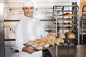 Happy baker showing tray of fresh bread