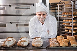 Happy baker standing near tray with bread