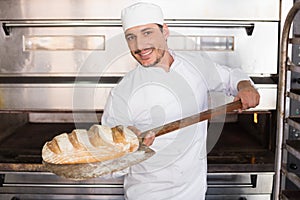 Happy baker taking out fresh loaf