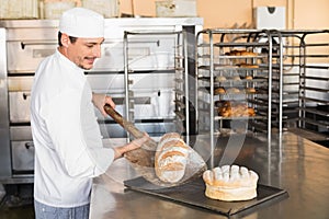 Happy baker taking out fresh loaf