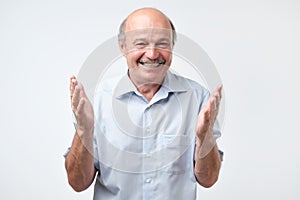 Happy bald senior man bragging about the big size of something photo