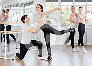 Happy ballet couple partners preparing in rehearsal for contest, training ballet poses with support in classroom