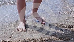 Happy barefoot child have fun on beach walk. Girl run along sea surf by water pool and jump with splashes. Summer