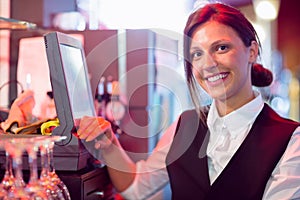 Happy barmaid using touchscreen till