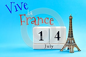 Happy Bastille day and French national day concept with a block calendar set on July 14, a miniature of the Eiffel Tower isolated