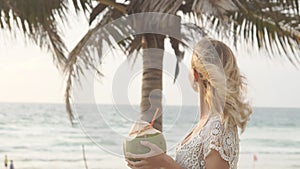 Happy beach bikini woman relaxing drinking fresh coconut water lying down sunbathing on fun Caribbean vacation