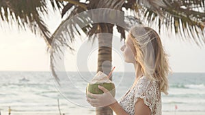 Happy beach bikini woman relaxing drinking fresh coconut water lying down sunbathing on fun Caribbean vacation