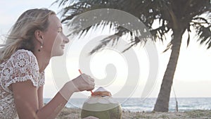 Happy beach bikini woman relaxing drinking fresh coconut water lying down sunbathing on fun Caribbean vacation