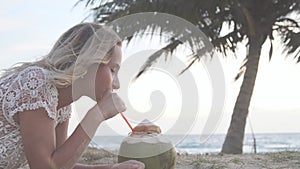 Happy beach bikini woman relaxing drinking fresh coconut water lying down sunbathing on fun Caribbean vacation