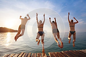 Happy beach holidays, group of friends jumping to water