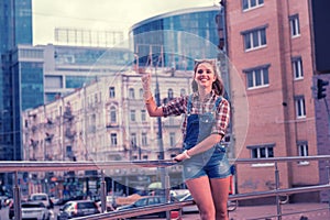 Happy beaming girl waving her friends while meeting them in the city center