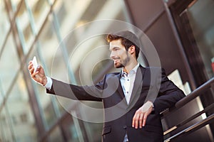 Happy bearded businessman standing outside office building