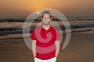 happy bearded handsome man in summer shirt on beach with sunset over sea, summer