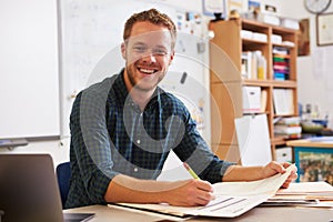 Happy bearded male teacher at desk looking to camera