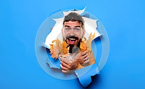 Happy bearded man with autumn leaves looking through paper hole. Autumn sales. Discount. Season sales. Smiling man in