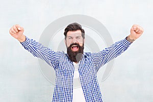 Happy bearded man celebrate victory keeping arms upward fingers clenched winning gestue blue background, winner