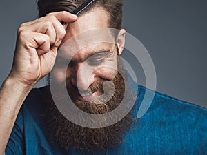 Happy bearded man combing his hair