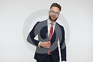 Happy bearded man with glasses fixing and unbuttoning suit