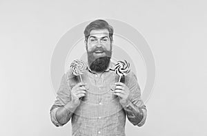 Happy bearded man hold tasty rainbow swirl candy pops great for birthday party and candy buffet yellow background