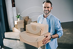 happy bearded man holding boxes and smiling at camera
