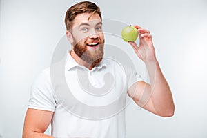 Happy bearded man holding green apple and looking at camera