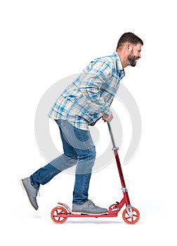 Happy bearded man rides a red kick scooter, isolated on white background. Side view