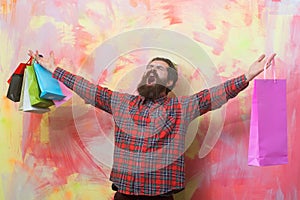 Happy bearded man shouting with colorful paper shopping bags