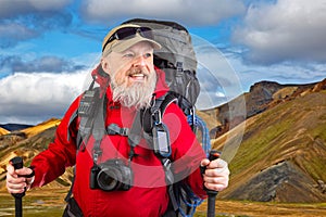 happy bearded man traveler with hiking equipment against the backdrop of a mountain landscape. travel, hiking and adventure