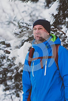 Happy bearded man, traveler walking in the winter forest