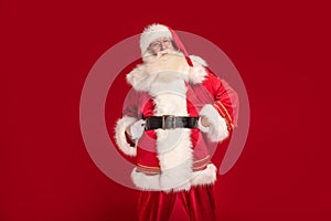 Happy bearded Santa Claus smiling to the camera, posing on red studio background. Merry Christmas and Happy New Year! A lot of