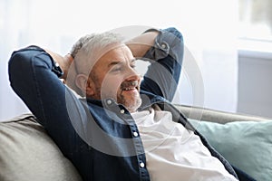 Happy bearded senior man relaxing on couch at home, closeup