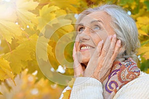 Happy beautifil elderly woman posing in autumn park