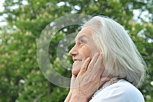 Portrait of happy beautifil elderly woman posing in summer park