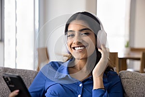 Happy beautiful 20s Indian student girl listening to music