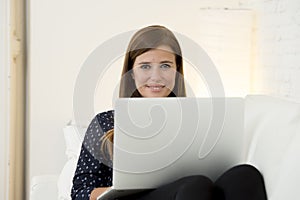 Happy beautiful 30s woman using laptop computer smiling networking at home modern living room relaxed