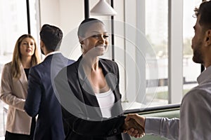 Happy beautiful African American businesswoman in formal suit shaking hands