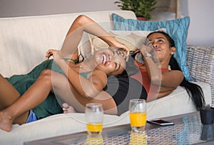 Happy beautiful Asian gay girlfriends couple laughing cheerful together having fun at home sofa couch cuddling and enjoying in wom