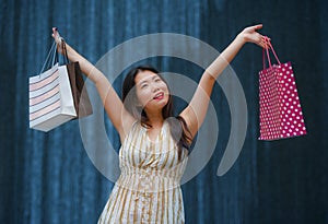 Happy and beautiful Asian Korean woman walking on the street posing on background smiling cheerful carrying shopping bags