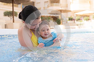 happy and beautiful Asian woman holding her little baby girl playful - Korean mother and adorable daughter playing on water at