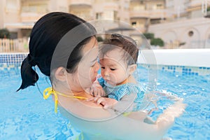 happy and beautiful Asian woman holding her little baby girl playful - Korean mother and adorable daughter playing on water at